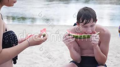 孩子们，青少年在海滩上休息，笑着<strong>吃西瓜</strong>，慢动作<strong>视频</strong>。 男孩和女孩休息